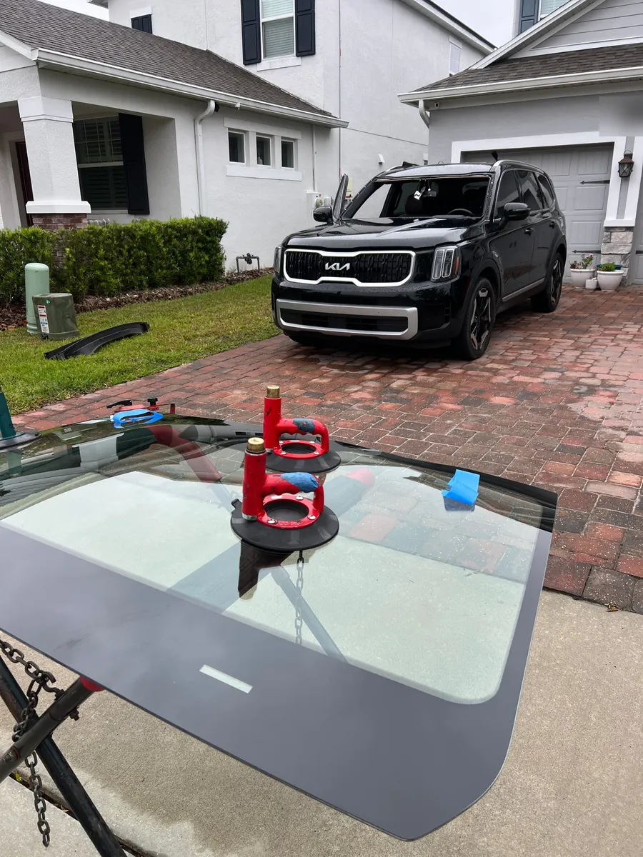New windshield on suction cups ready to install on a Kia Telluride in a Winter Garden, FL driveway